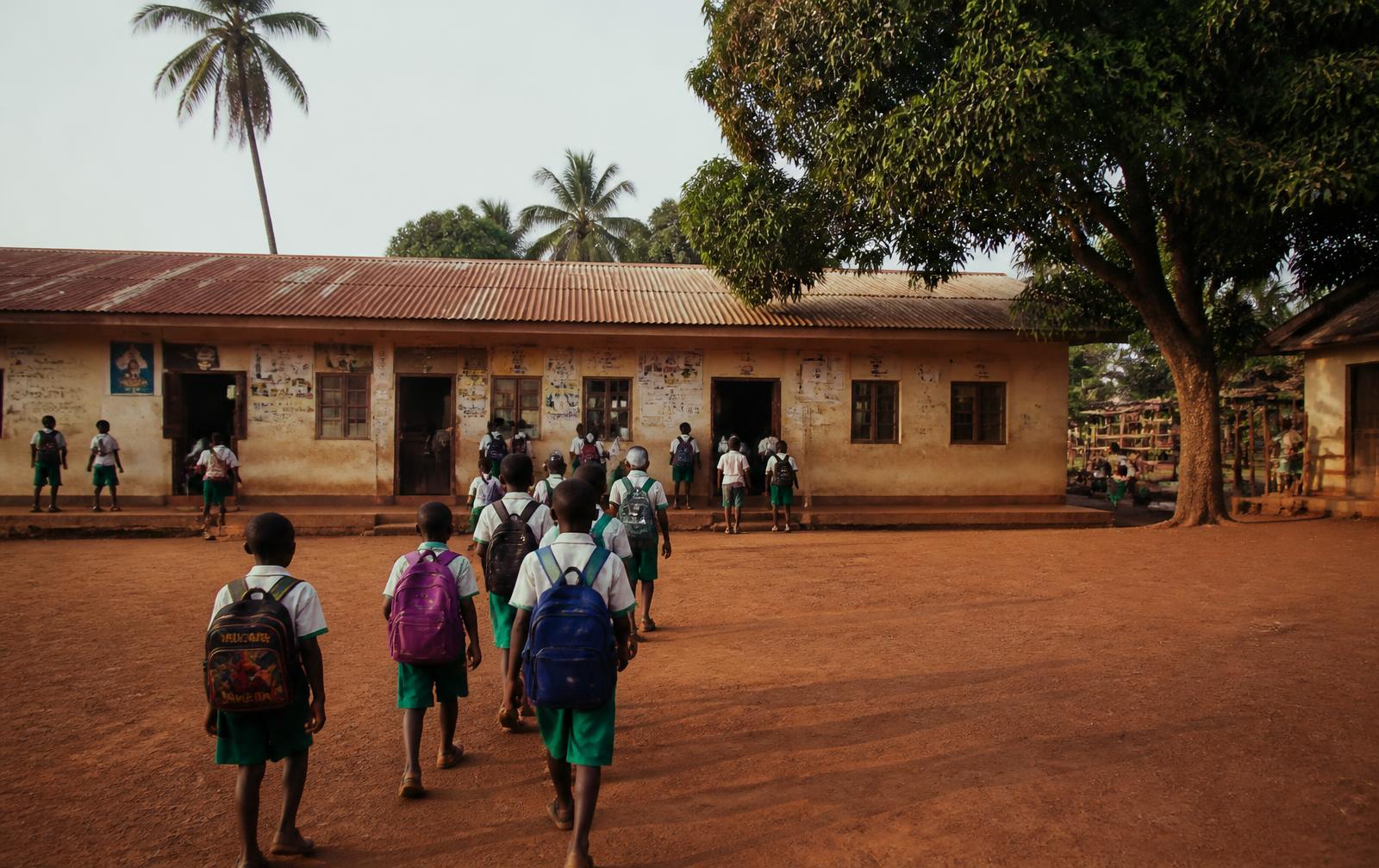 Élève écrivant devant une école de village